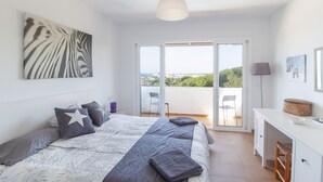 A bedroom with a bed, a desk, and a balcony with a view. - 3 Bedroom Villa, private pool,  stunning Sea Views 5 mins from beach. WIFI & AC (Arenal D'en Castell)