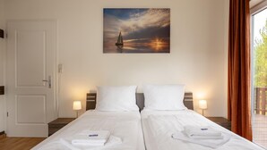 Hotelkamer met twee bedden, een schilderij van een zeilboot aan de muur en uitzicht op de omgeving.