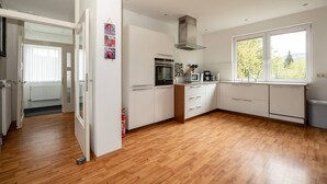 Een moderne keuken met witte kasten, een magnetron, oven en een groot raam.