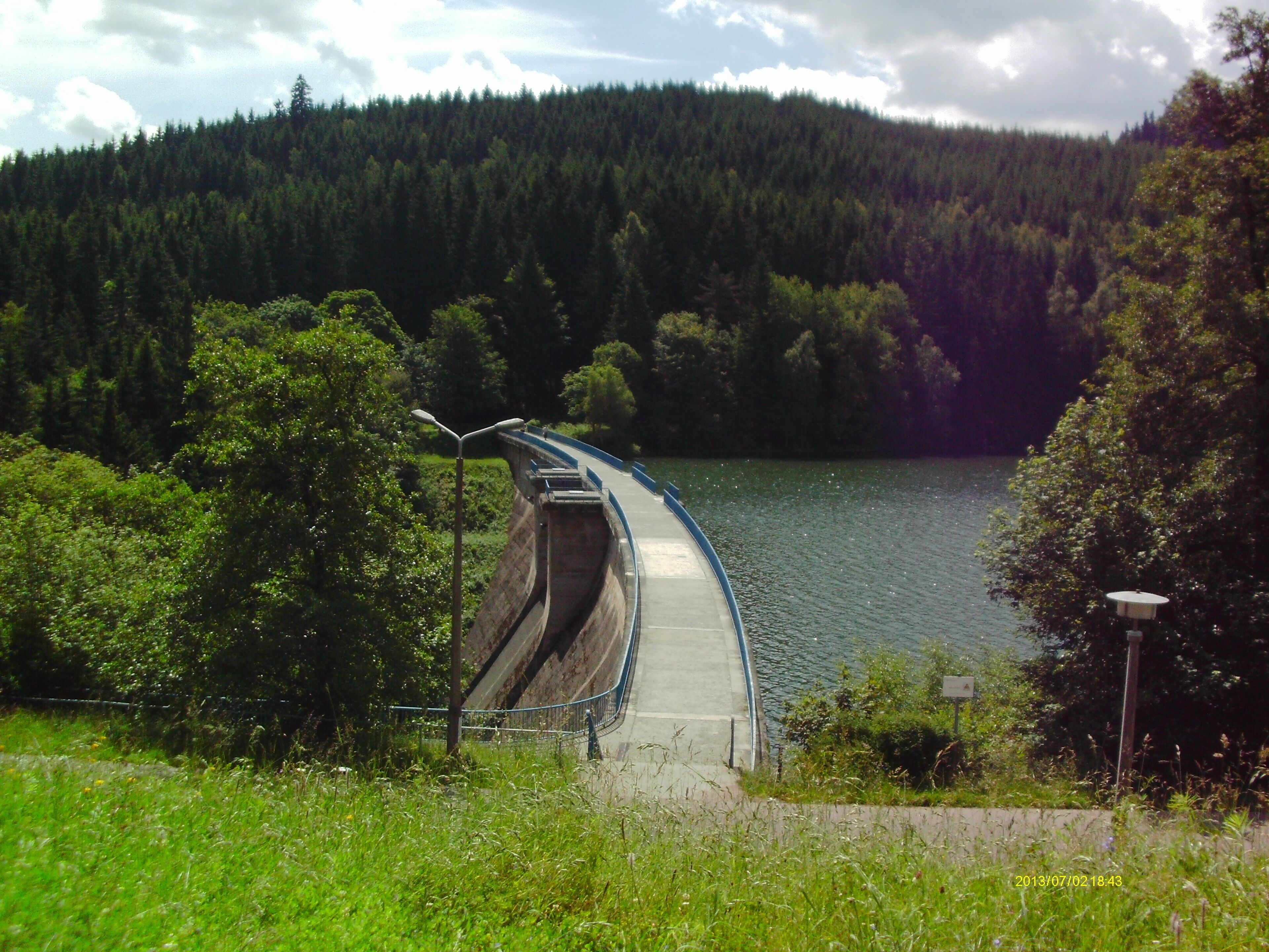 A bridge over a river with a forested hillside in the background.