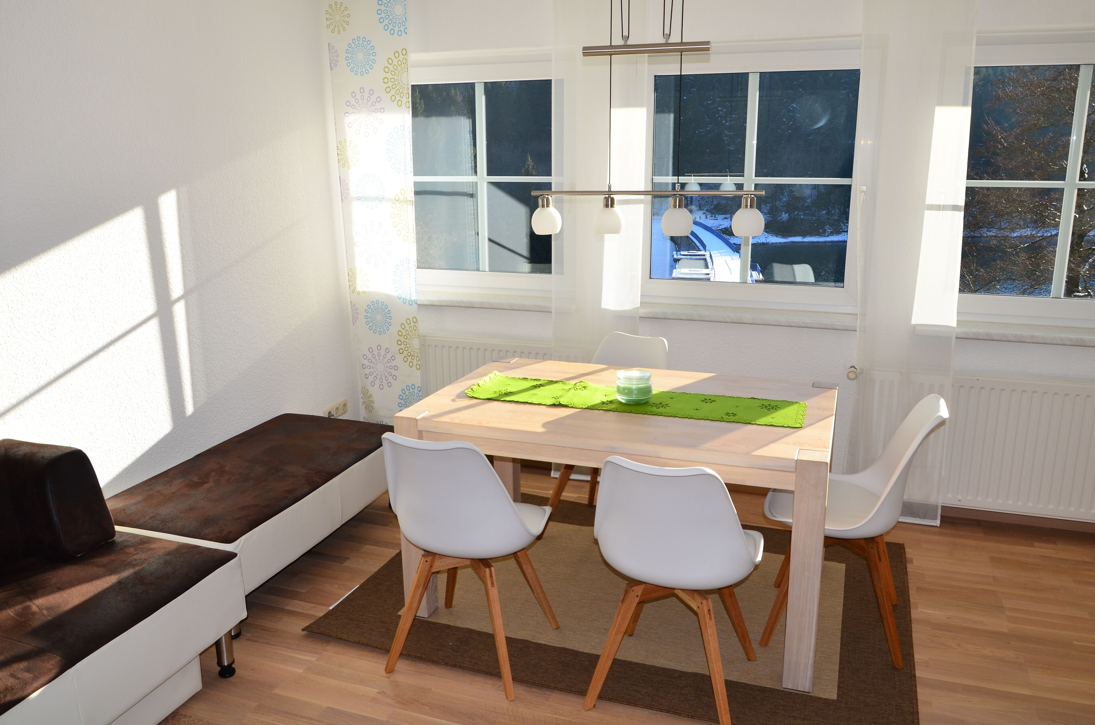 A modern dining area with a wooden table, white chairs, and a bench.
