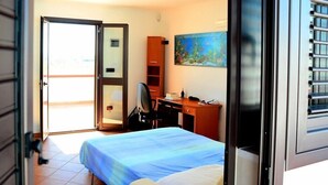 A hotel room with a bed, a desk, a chair, a small cabinet, and a painting on the wall. - Beautiful architect villa, sea views, WiFi (Torre Santa Sabina)