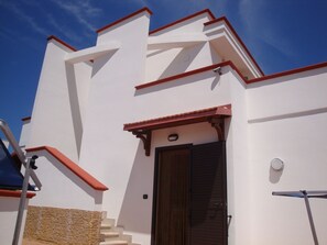 Un bâtiment blanc avec un toit rouge et une porte en bois.