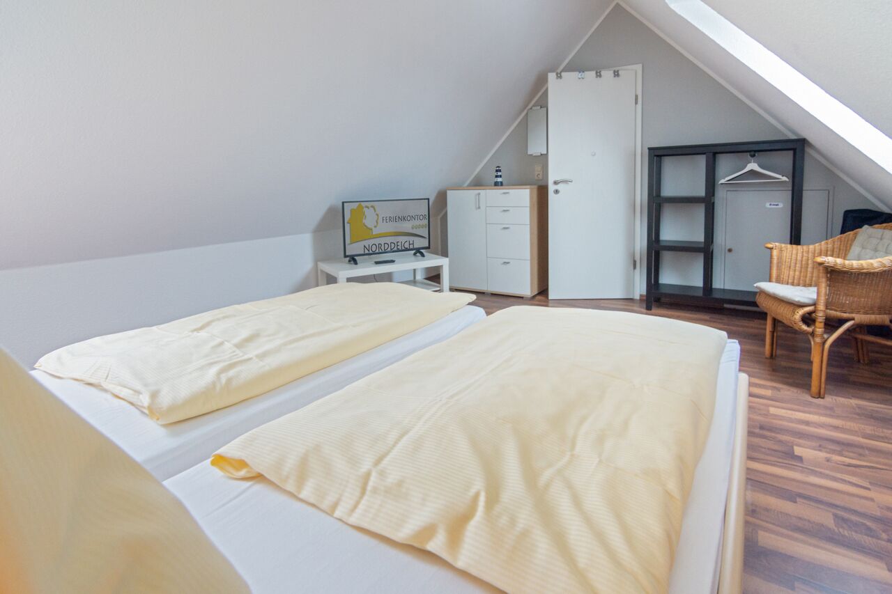 Ein Zimmer mit zwei Betten, einem Schreibtisch mit einer Karte, einem Kleiderschrank und einem Hängekorbsessel.