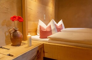 A wooden bed with white bedding, a vase with red flowers, and checkered pillows. - Fürstenpalais holiday apartment in the tower of Schedling Castle near Lake Chiemsee (Trostberg)