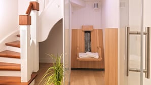 Un baño moderno con un banco de madera, mampara de ducha de vidrio y una toalla blanca sobre el banco.