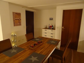 Un coin repas avec une table en bois, des sets de table à motifs étoilés et un plateau de boissons.