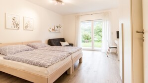 Un dormitorio con cama, escritorio y ventana con cortinas.