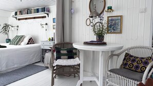 Ein Zimmer mit einem Bett, einem Sessel, einem kleinen Tisch und einem Regal mit Büchern.