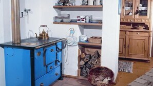 A kitchen with a blue cabinet, a stove, shelves with dishes, and a wooden cabinet. - secluded, 300 year old landmarked Holiday Home, renovated (Bayern)