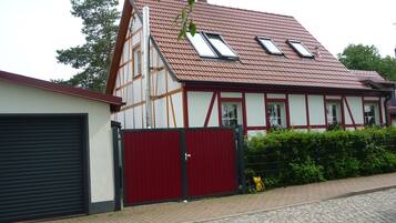 A traditional half-timbered house with a red roof, two skylights, and a red gate.