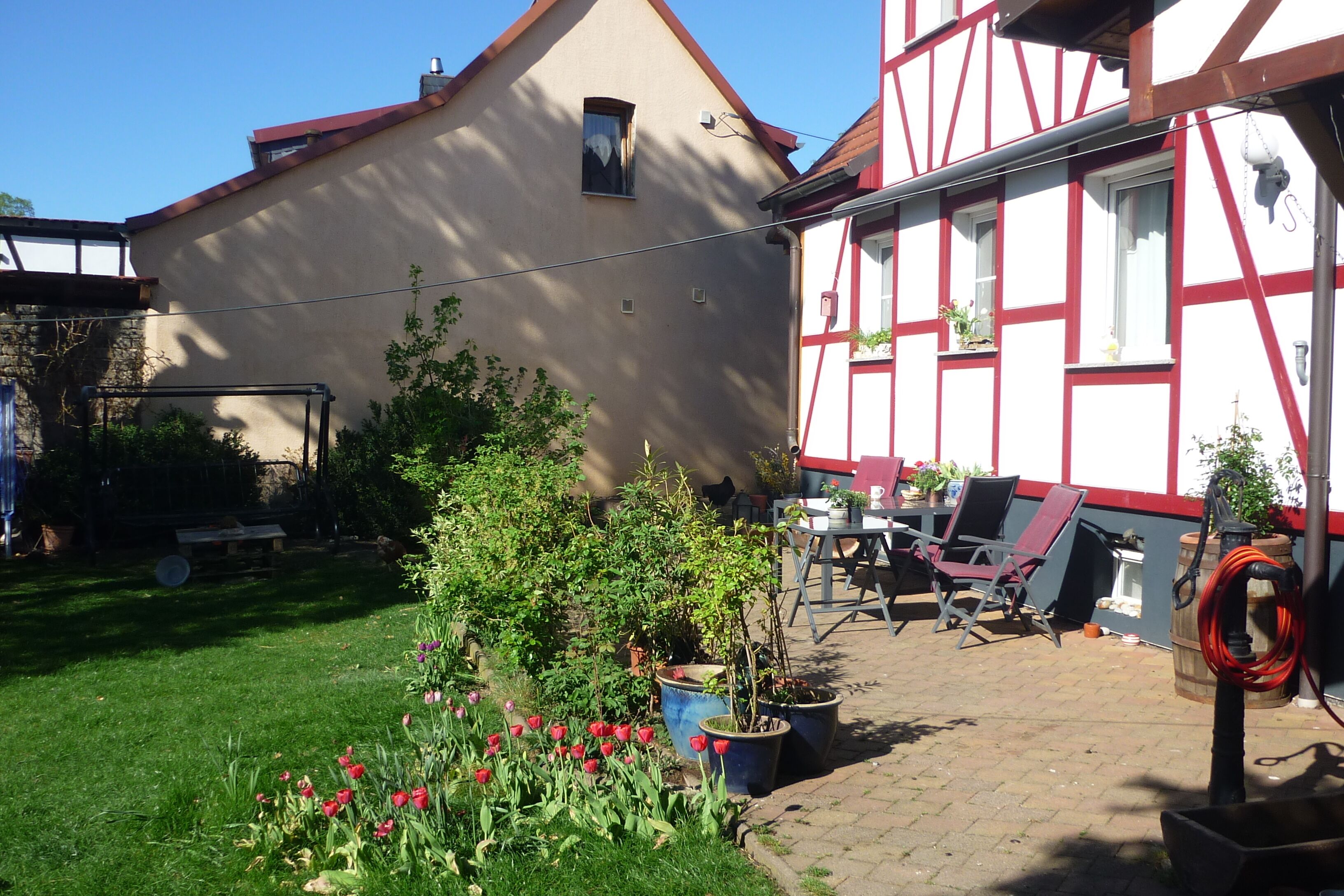 Uma casa tradicional em enxaimel com um jardim repleto de tulipas e plantas em vasos.
