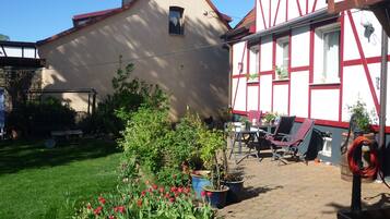 Uma casa tradicional em enxaimel com um jardim repleto de tulipas e plantas em vasos.