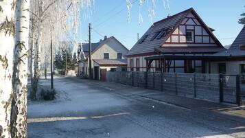A snow-covered street with traditional houses, a clear sky, and bare trees.