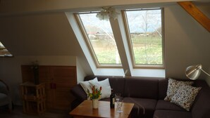 Uma sala de estar aconchegante com uma mesa de madeira, um sofá e uma janela com vista para um campo.