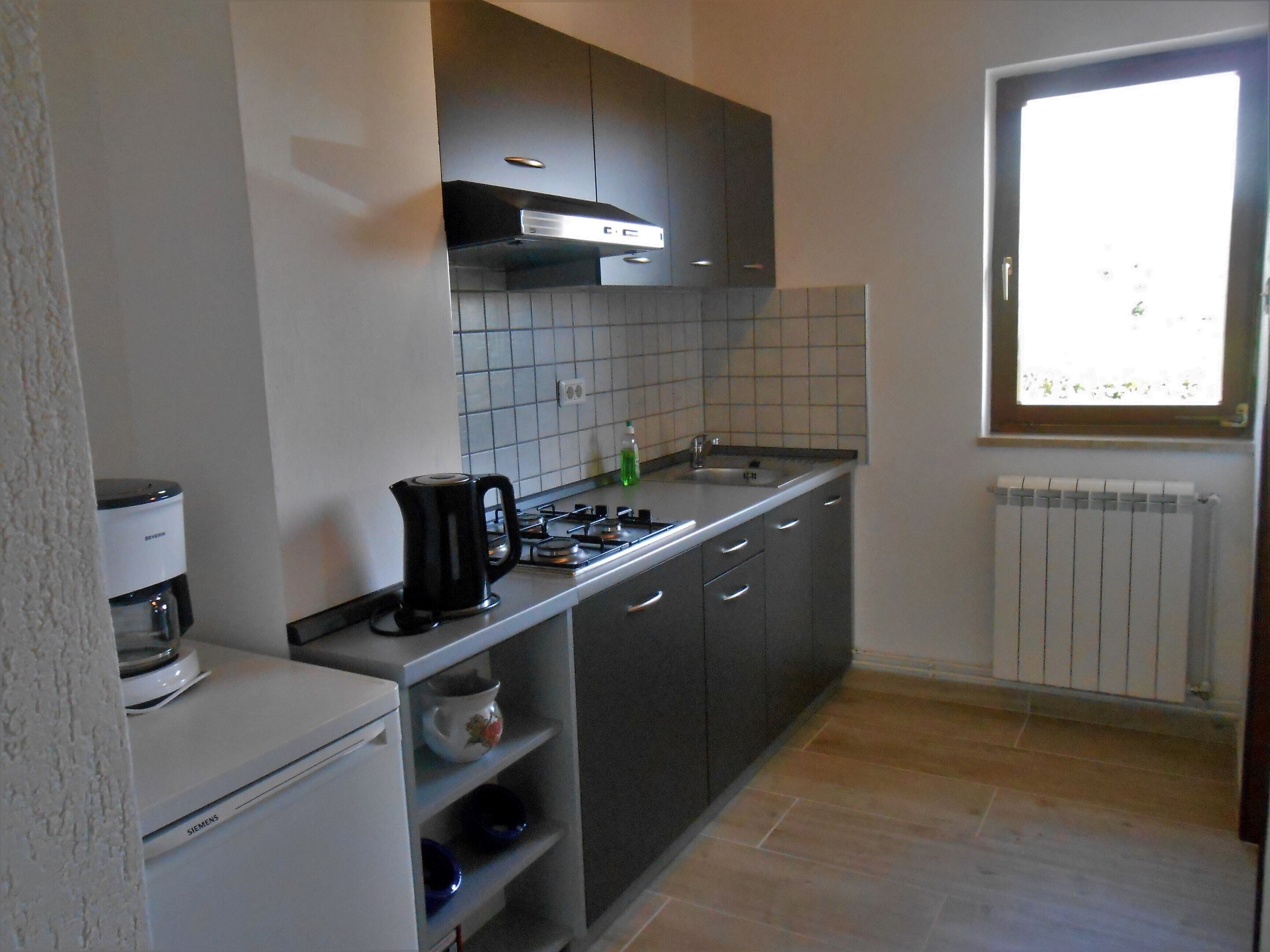 A compact kitchen with a gas stove, a coffee maker, and a built-in oven.