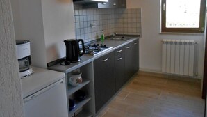 Una cucina compatta con piano cottura a gas, macchina da caffè e forno integrato.