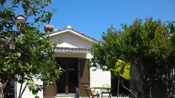 Una casa con tetto in tegole, una porta d'ingresso e un piccolo patio con tavolo e sedie.