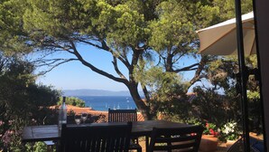 An outdoor patio with a table and chairs, overlooking a scenic view of the sea and mountains. - Côte d'Azur villa with stunning sea views for rent on the Giens Peninsula (Hyères)