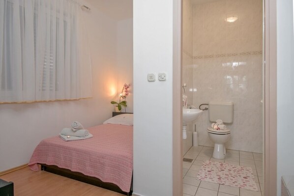 A bedroom with a bed, a bedside table with a lamp, and a bathroom with a toilet and sink. - Room in Bol with Terrace, Air condition, WIFI (3758-4) (Bol)