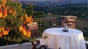Une table dressée à l’extérieur, avec une vue sur la montagne, une chaise et un vase décoratif.