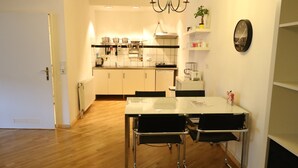 A modern kitchen with white cabinets, a white countertop, and a dining area with two black chairs. - Apartment in the heart of Kreuzberg, loft,art,pubs,bars,nightlife,WiFi,up to 4 persons  (Bezirk Friedrichshain-Kreuzberg)