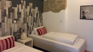 A bedroom with two beds, a brick wall, and a mural. - Apartment in the heart of Kreuzberg, loft,art,pubs,bars,nightlife,WiFi,up to 4 persons  (Bezirk Friedrichshain-Kreuzberg)