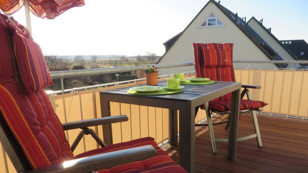 A deck with a table set for two, two chairs, and a potted plant. - Stylish 3 rows App. up to 4 people + Toddler + wifi, 250 m to the Baltic Sea (Börgerend)