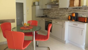 A compact kitchen with a dining area, featuring a microwave, stove, and modern appliances. - Stylish 3 rows App. up to 4 people + Toddler + wifi, 250 m to the Baltic Sea (Börgerend)