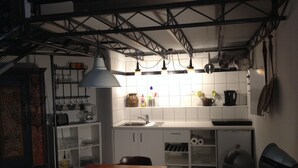 Una cocina compacta con armarios blancos, una mesa de comedor de madera y una lámpara colgante.