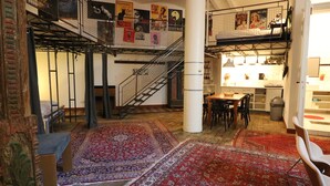 Un loft espacioso con techo alto, paredes de ladrillo visto y un nivel entre piso.