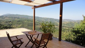 A covered patio with a table and chairs, overlooking a mountainous landscape. - Apartment with a beautiful panoramic terrace on the Cilento coast (Ogliastro Cilento)