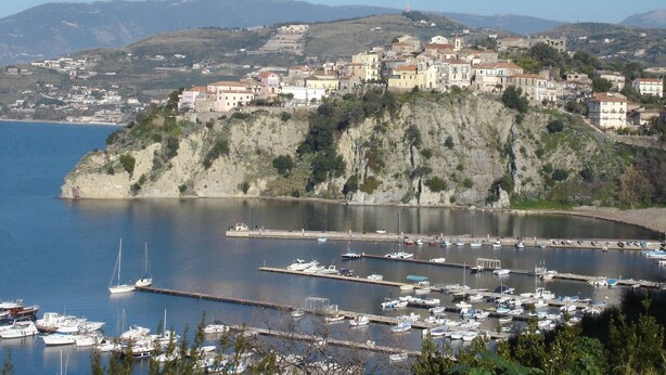A coastal town with buildings on a hillside overlooking a marina with boats. - Apartment with a beautiful panoramic terrace on the Cilento coast (Ogliastro Cilento)