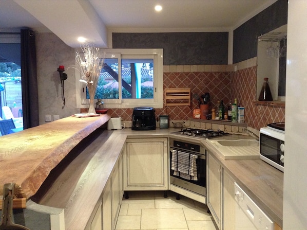 A modern kitchen with a wooden countertop, a built-in stove, and a window with a view of the outside.