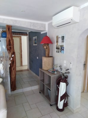 A hallway with a wooden cabinet, a red lamp, and a wall-mounted air conditioner.