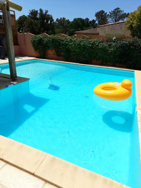 Una piscina rectangular con superficie de agua azul cristalina, rodeada por una solana con baldosas.