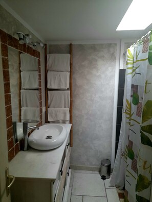 Un baño con lavamanos blanco, espejo y perchero.