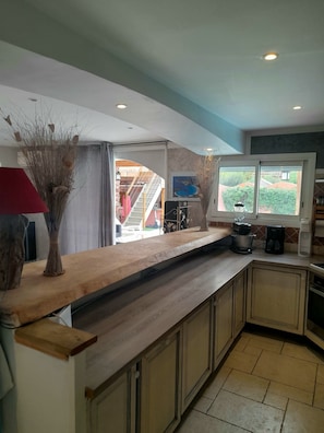 A kitchen with a long countertop, cabinets, a window with a view, and a ceiling with recessed lighting.