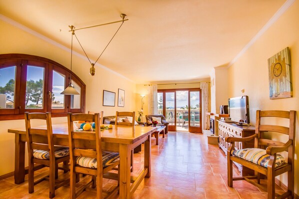 Un amplio salón con una mesa de comedor de madera, sillas y un televisor.