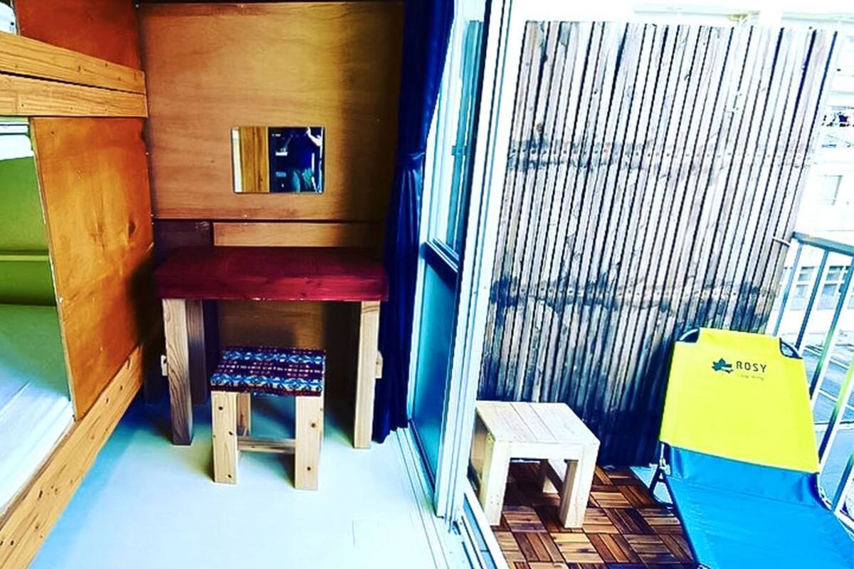 Une petite pièce comprenant un lit superposé, un petit bureau en bois et une chaise.
