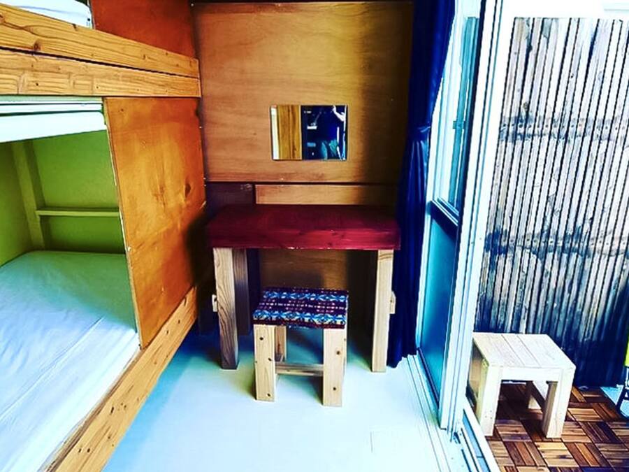 A compact room with a bunk bed, a small wooden desk, and a chair.