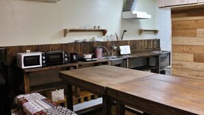 Een kleine keuken met houten aanrecht, een magnetron, een koffiezetapparaat en een spoelbak.