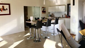 Eine moderne Küche mit weißen Schränken, ein Essbereich mit einem Holztisch und schwarzen Stühlen sowie ein großes Fenster für natürliches Licht.