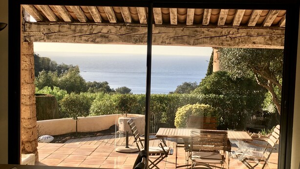 Eine Terrasse mit Tisch und Stühlen, Meerblick und einer Pergola.