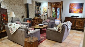 Un salon chaleureux avec une cheminée, des canapés, une table basse et une bibliothèque.