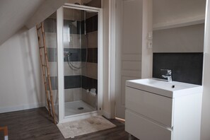 Een badkamer met een glazen douchecabine, een wit wastafelmeubel en een houten ladder tegen de muur.