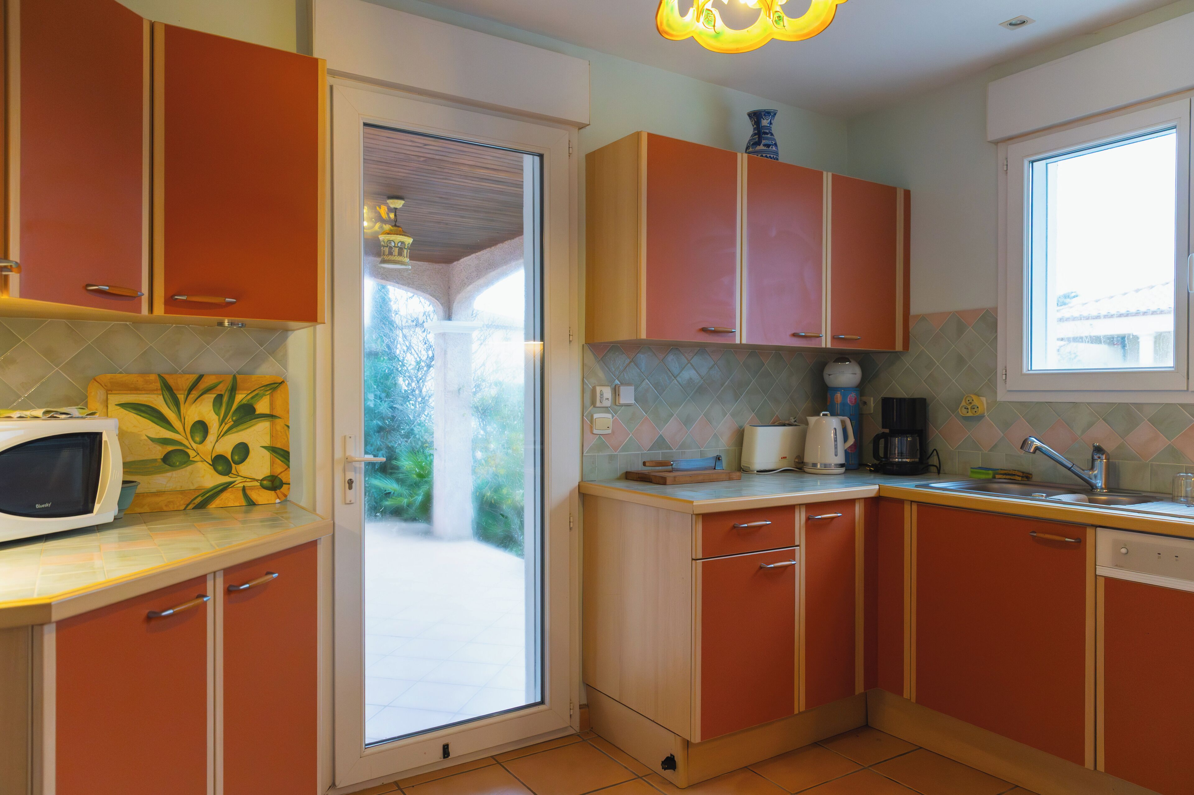 A kitchen with wooden cabinets, a microwave, and a window.