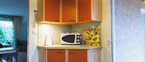 A compact kitchen with orange cabinets, a microwave, and a small countertop.