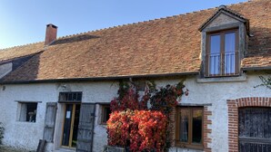 A rustic house with a tiled roof, a brick chimney, and a small balcony with metal railings. - Le Colombier Guesthouse (Concriers)
