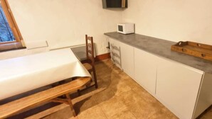 Une petite cuisine équipée d’un four à micro-ondes, d’un banc en bois et d’une petite table.